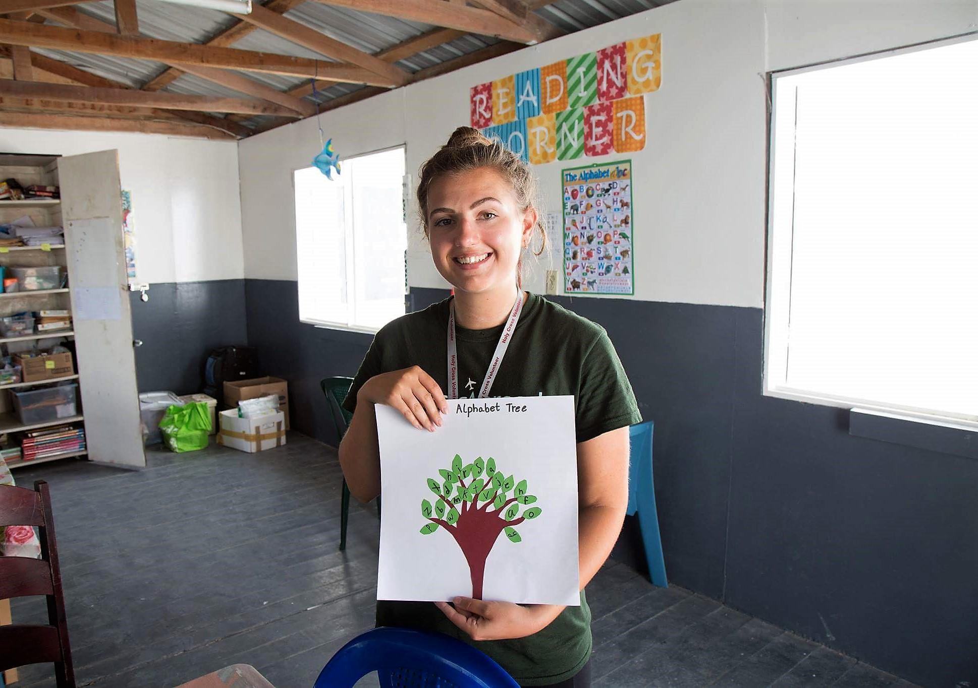 A volunteer teaching in Belize holds up an alphabet tree created by one of her students on the literacy project Projects Abroad volunteer holds up an alphabet tree created by one of her students at her Teaching placement in Belize